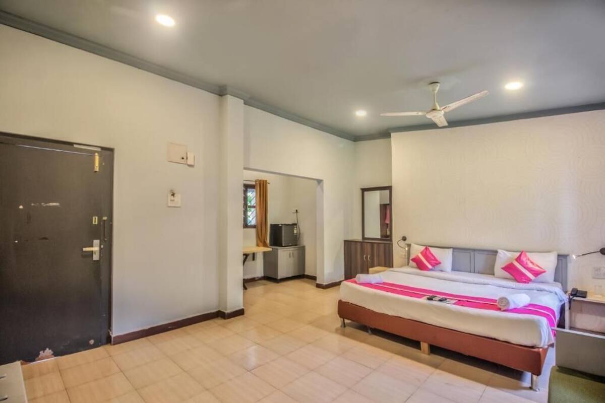 A bedroom with a bed, a ceiling fan, a wardrobe, and a desk with a chair.