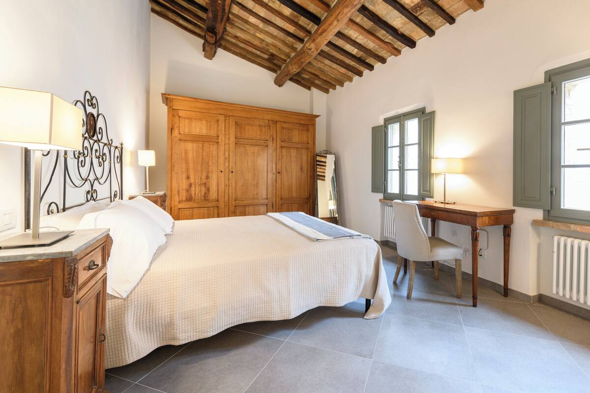 Un dormitorio con cama, armario de madera, escritorio y silla.