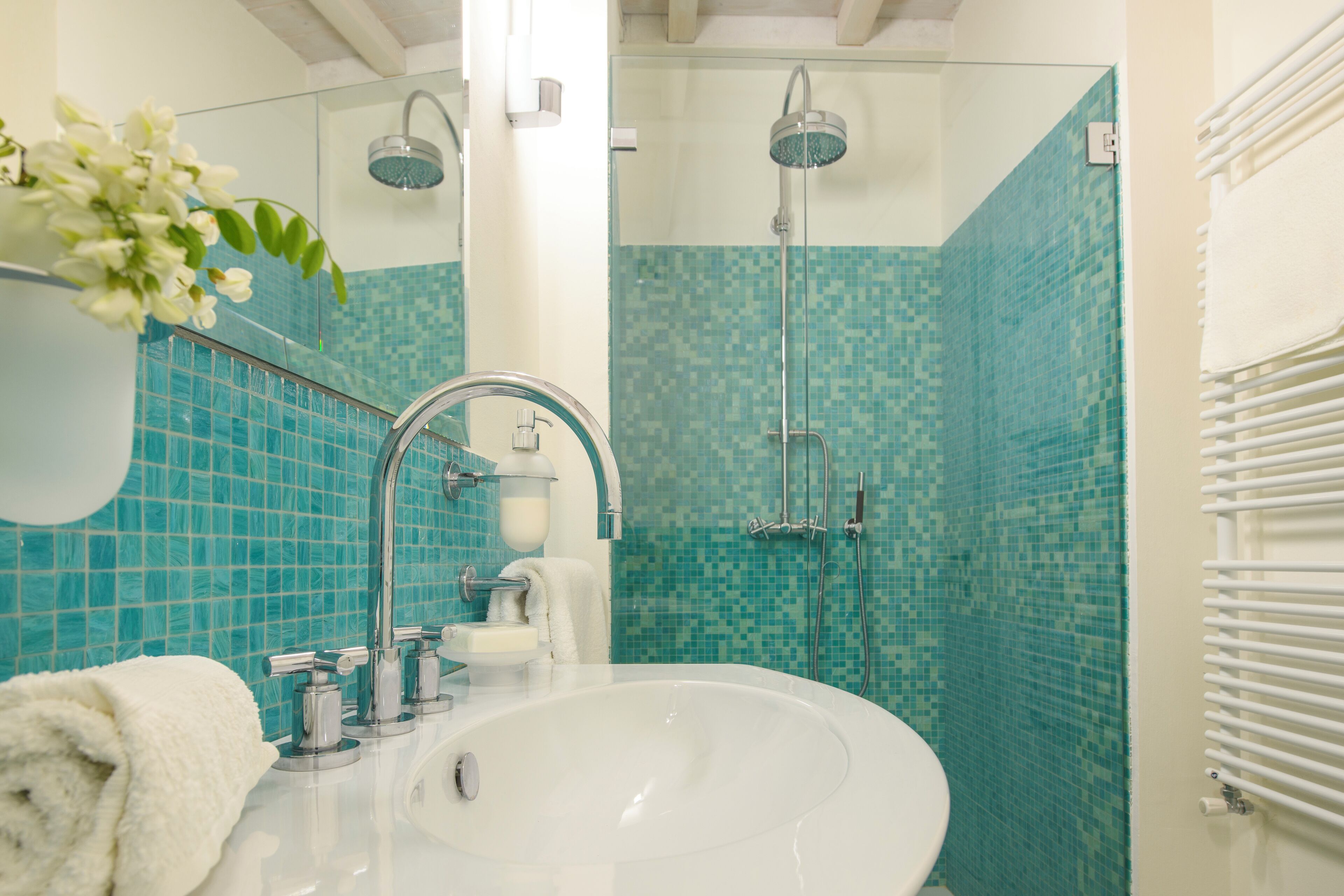 Une salle de bain avec un lavabo blanc, une cabine de douche en verre et un mur carrelé.