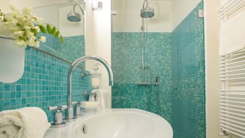Une salle de bain avec un lavabo blanc, une cabine de douche en verre et un mur carrelé.