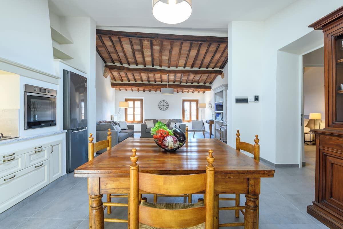 Una cocina amplia con una mesa de comedor de madera, armarios blancos y un horno empotrado.