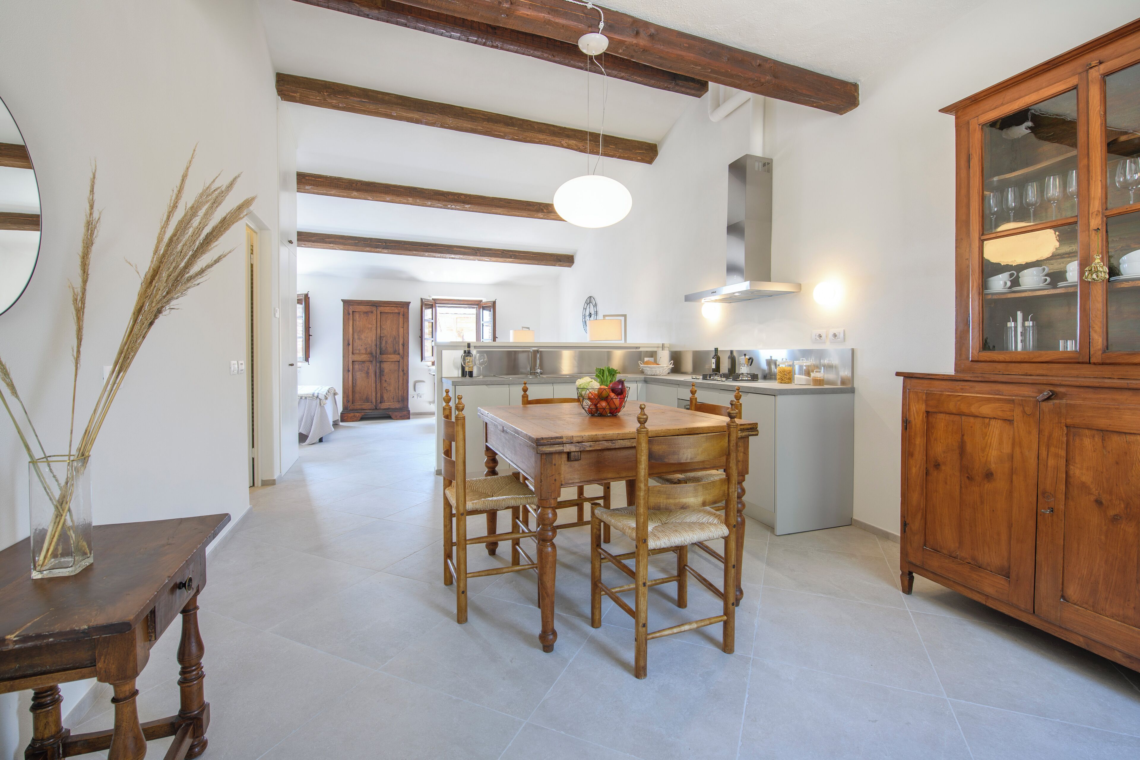 Une cuisine spacieuse avec une table à manger en bois, des chaises et un buffet aux portes vitrées.
