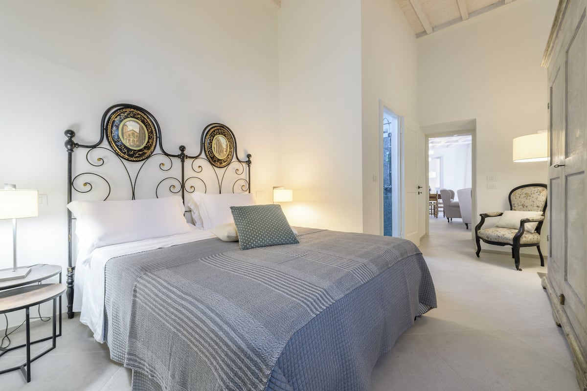 Un dormitorio ordenado con cama, mesita de noche y una silla.
