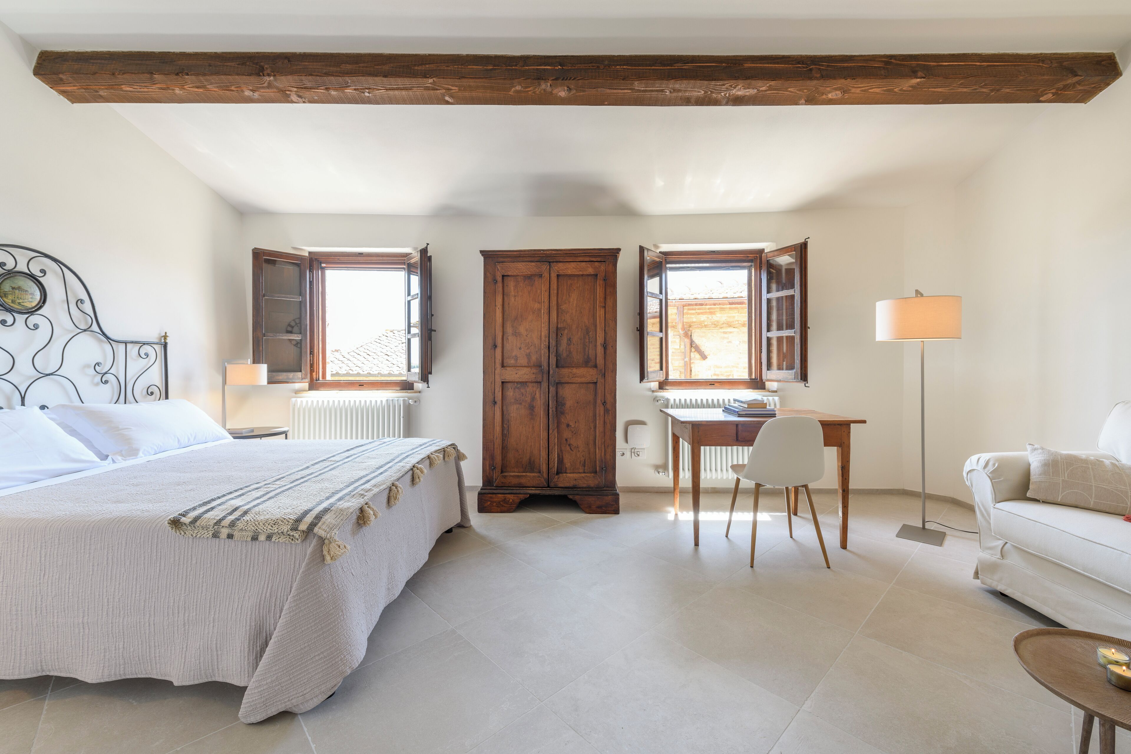 Ein Schlafzimmer mit Bett, Schreibtisch, Stuhl und einem kleinen Tisch mit Kerzen.