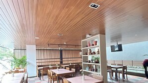 A modern indoor space with wooden ceiling panels, checkered flooring, and a variety of seating arrangements including tables and chairs. - Gendhis Batu Boutique Hotel (Batu)