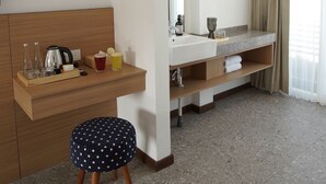 A hotel room with a wooden desk, a large mirror, a sink, and a small stool. - Gendhis Batu Boutique Hotel (Batu)