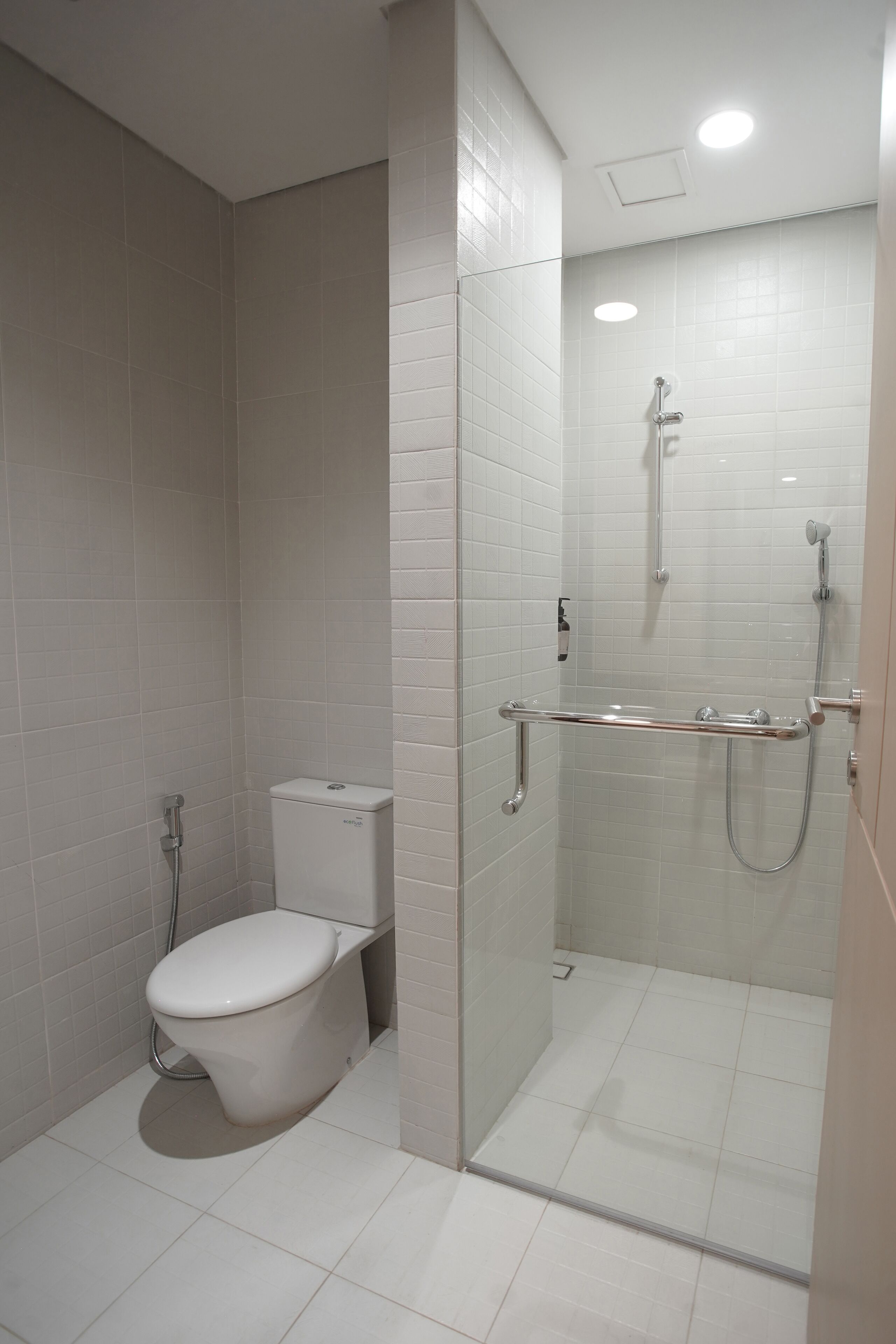 Une salle de bain moderne équipée de toilettes, d’une douche et d’une paroi de séparation en verre.