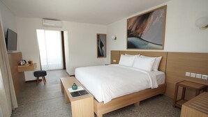 A modern hotel room with a large bed, a desk with a chair, a small stool, and a bench. - Gendhis Batu Boutique Hotel (Batu)