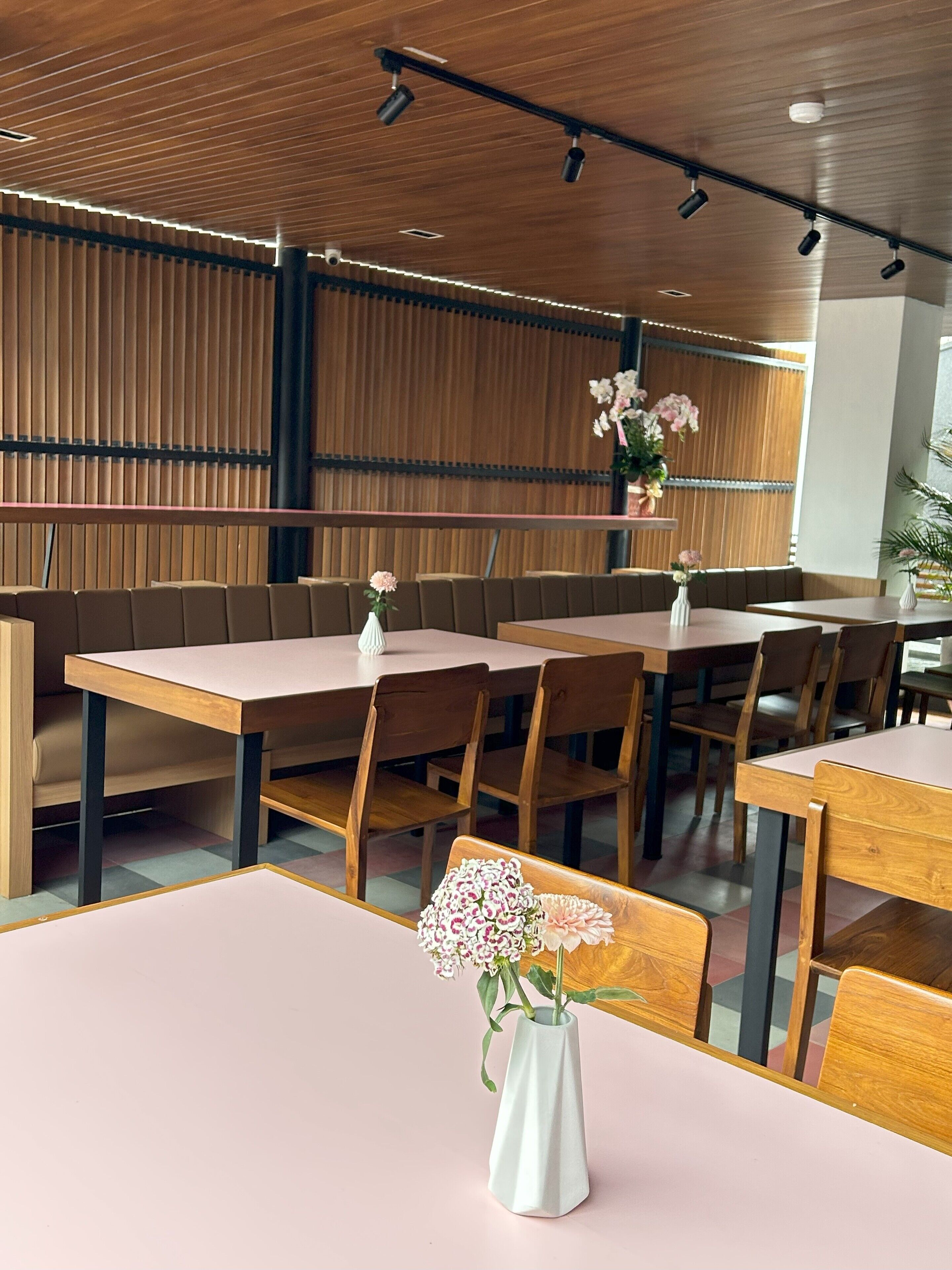 Een restaurant met houten lambrisering, tafels en stoelen.