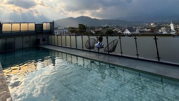 A rooftop pool with clear water, a view of the city, and a large cloud in the sky. - Gendhis Batu Boutique Hotel (Batu)