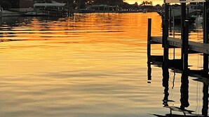 A waterfront scene with a dock and a building with a covered area. - Villa Meridian Spacious villa for discerning guests. (Cape Coral)