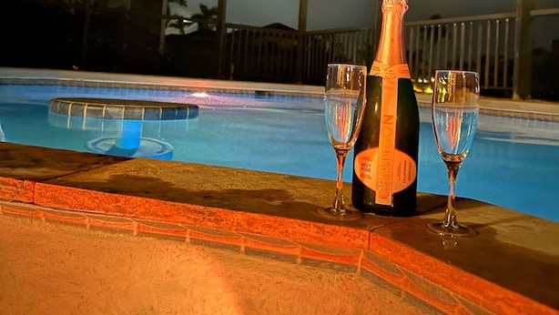 A bottle of Brut Rose champagne and two glasses on a poolside table. - Villa Meridian Spacious villa for discerning guests. (Cape Coral)
