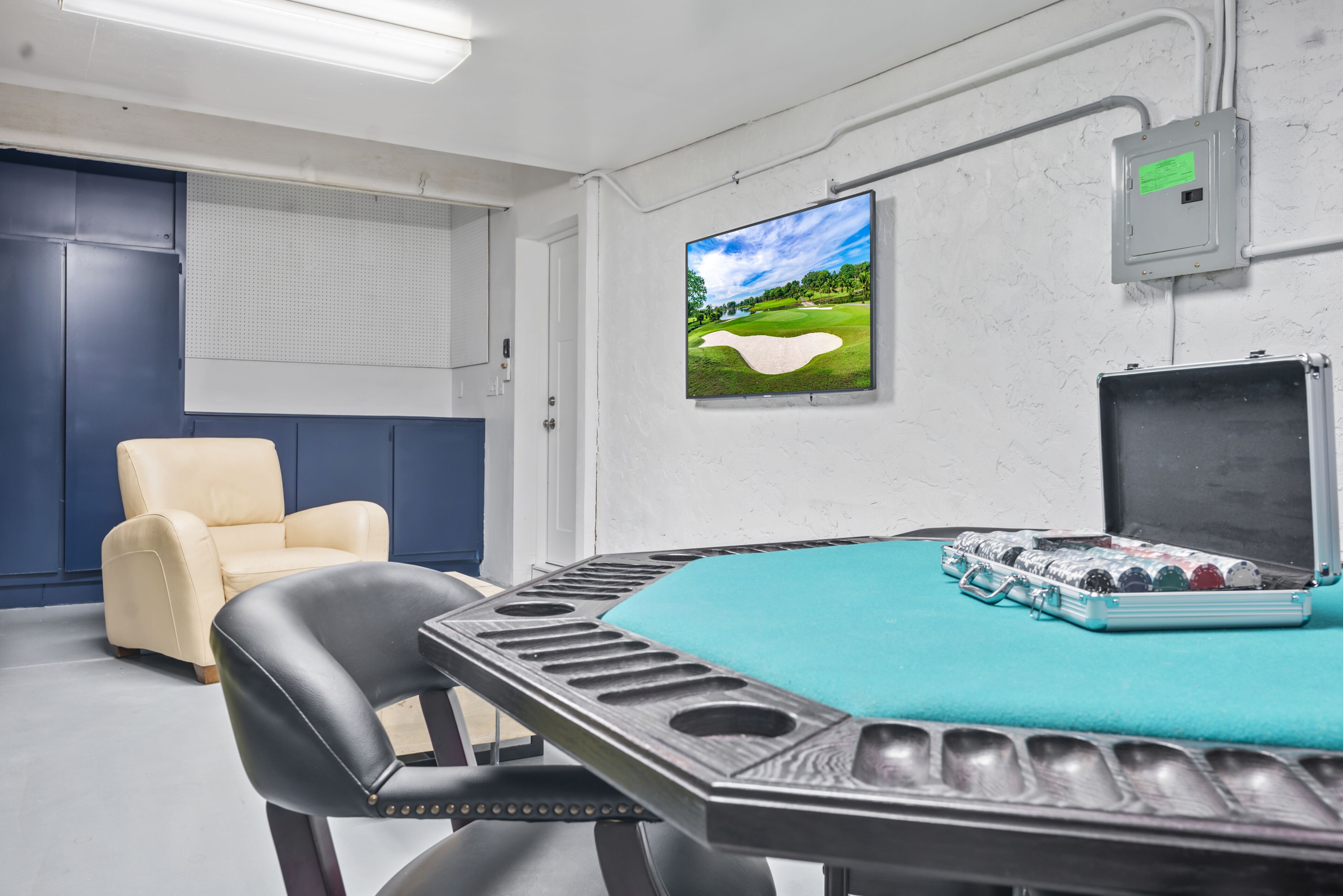 A conference room with a table, chairs, a projector screen, and a television displaying a golf course.