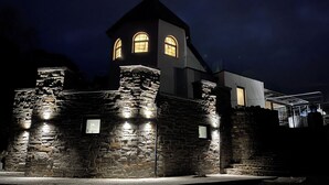 Een stenen gebouw met een toren, verlichte ramen en een stenen muur.