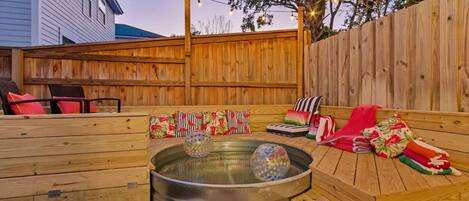 Eine Holzterrasse mit Whirlpool, Sitzgelegenheiten im Freien und Lichterketten.