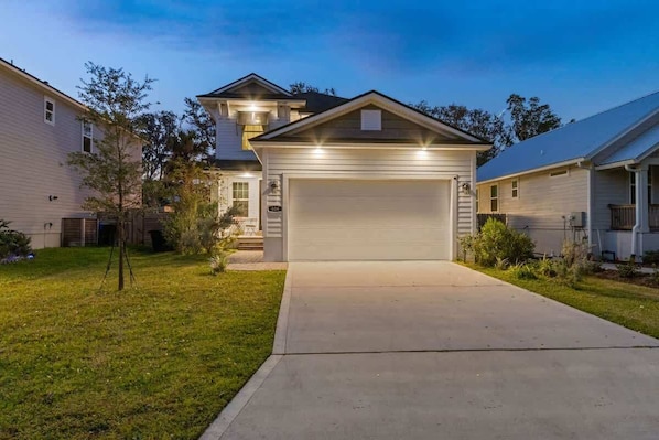 A residential house with a garage, a lawn, and a small tree.