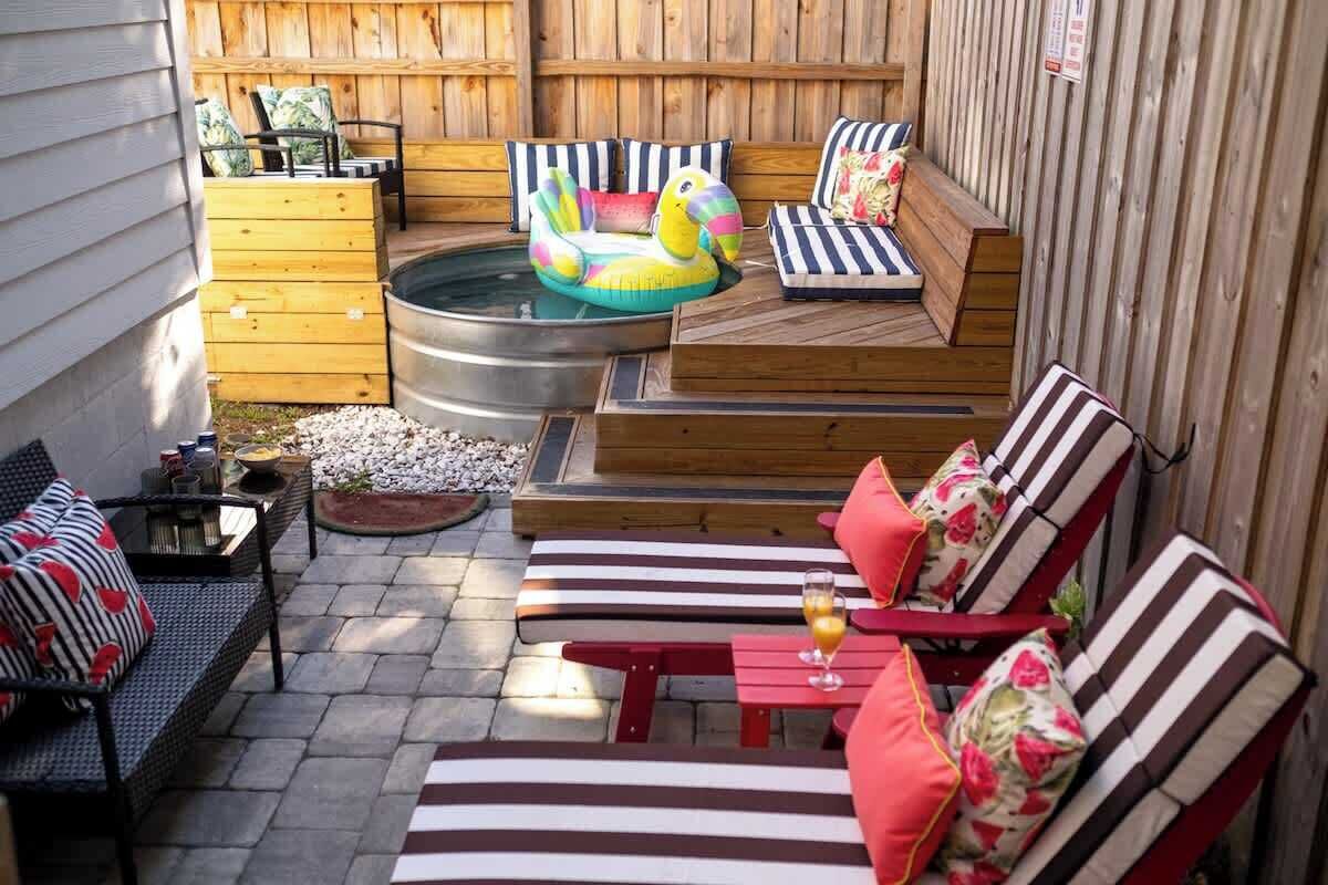 A backyard with a hot tub, lounge chairs, and a wooden deck.