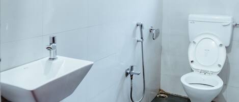 A bathroom with a white sink, a toilet, and a shower.