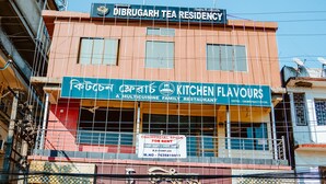 Un edificio con un cartel que indica 'Dibrugarh Tea Residency' y 'Kitchen Flavours' debajo.