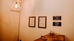 Una habitación con una mesa, documentos enmarcados en la pared y un cartel que indica la hora de salida y WiFi gratuito.