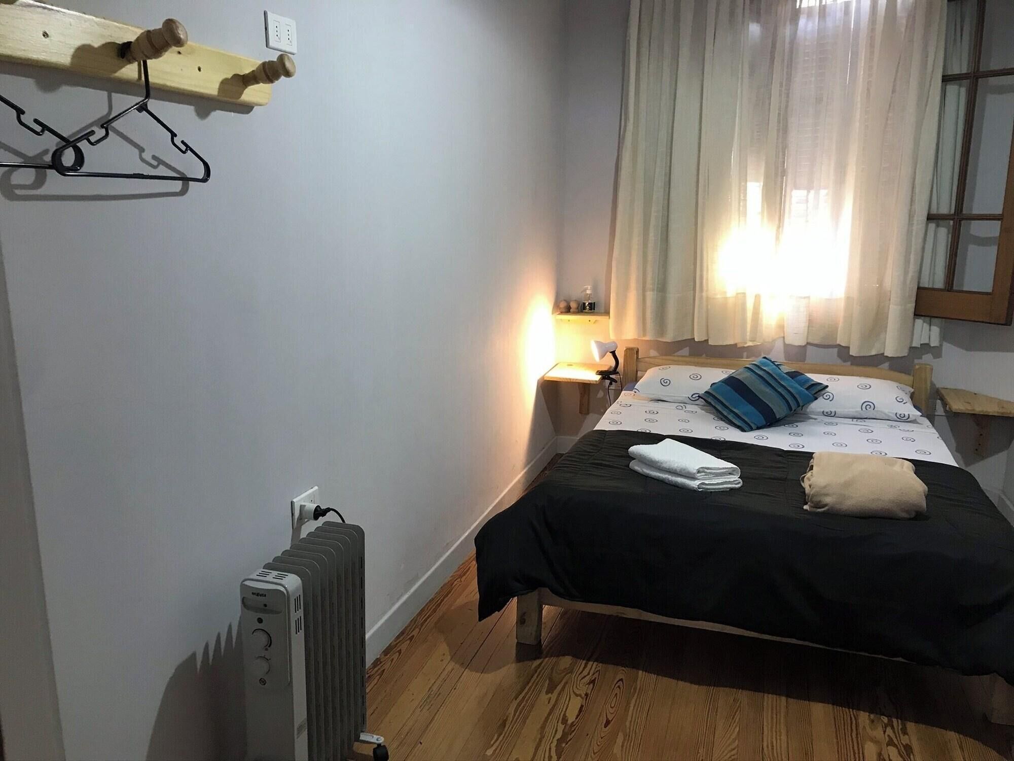 Une chambre à coucher avec un lit, une lampe de chevet, un radiateur et une fenêtre avec des rideaux.