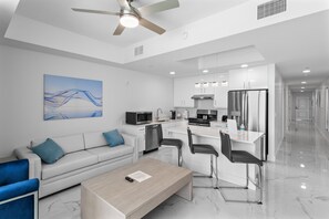 A modern living room with a sofa, coffee table, and a dining area with chairs.