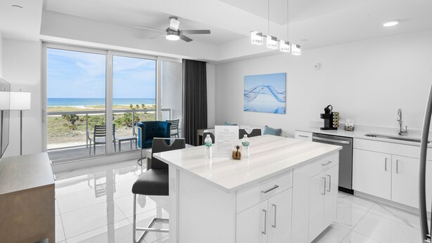 A modern kitchen with a large island, white cabinets, and a view of the beach. - New Tropical Resort Living on the Beach (Treasure Island)