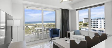 Habitación de hotel moderna con balcón, ventilador de techo, televisión y vista a la playa.