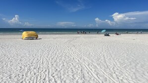 Una playa con una carpa amarilla y algunas personas.