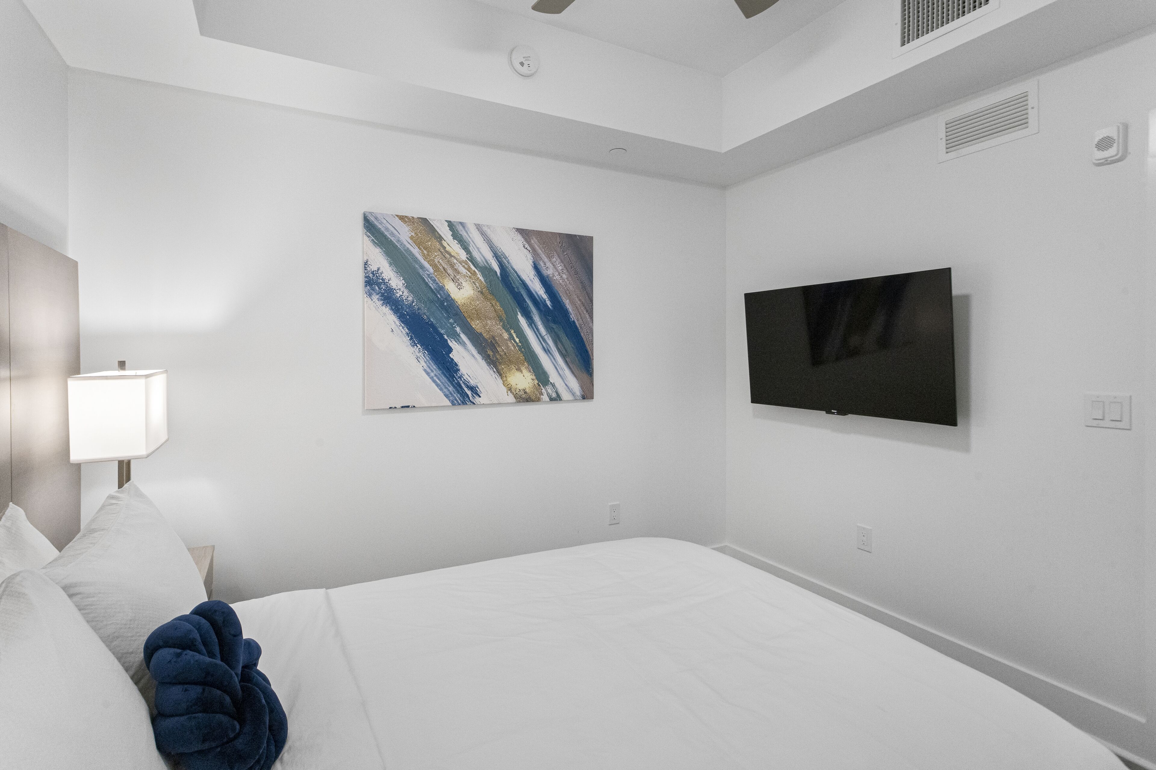 Habitación de hotel con una cama, un televisor de pantalla plana en la pared y un cuadro sobre la cama.
