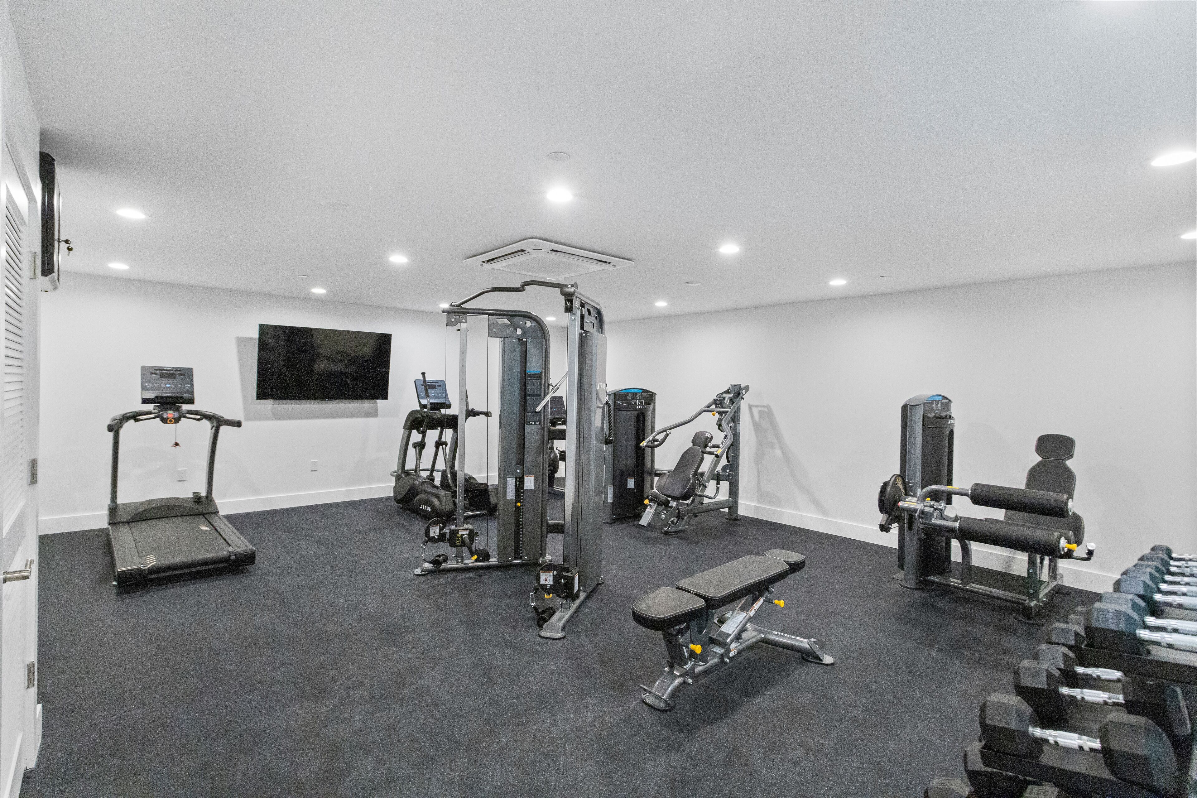 A gym with treadmills, weight machines, and dumbbells.