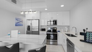 Una cocina moderna con armarios blancos, electrodomésticos de acero inoxidable y una isla central con asientos.