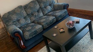 A living room with a patterned sofa, a dark coffee table, and a lamp. - Corner Shop Apartments Sleeps 5 Parking (Stoke-on-Trent)