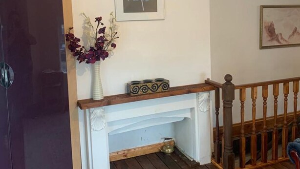 A room with a white fireplace, a framed picture above it, and a vase with flowers on a mantel. - Corner Shop Apartments Sleeps 5 Parking (Stoke-on-Trent)