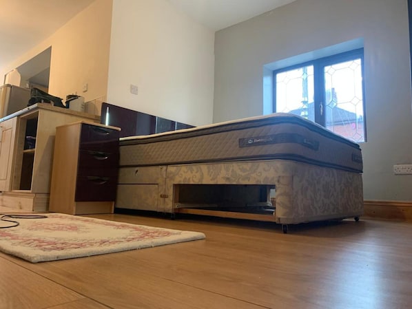 A bedroom with a Murphy bed, a wooden dresser, a rug, and a window with a view. - Corner Shop Apartments Sleeps 5 Parking (Stoke-on-Trent)