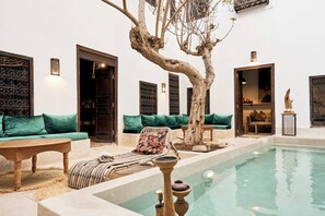 A poolside area with a lounge chair, a wooden table, and a small pool.
