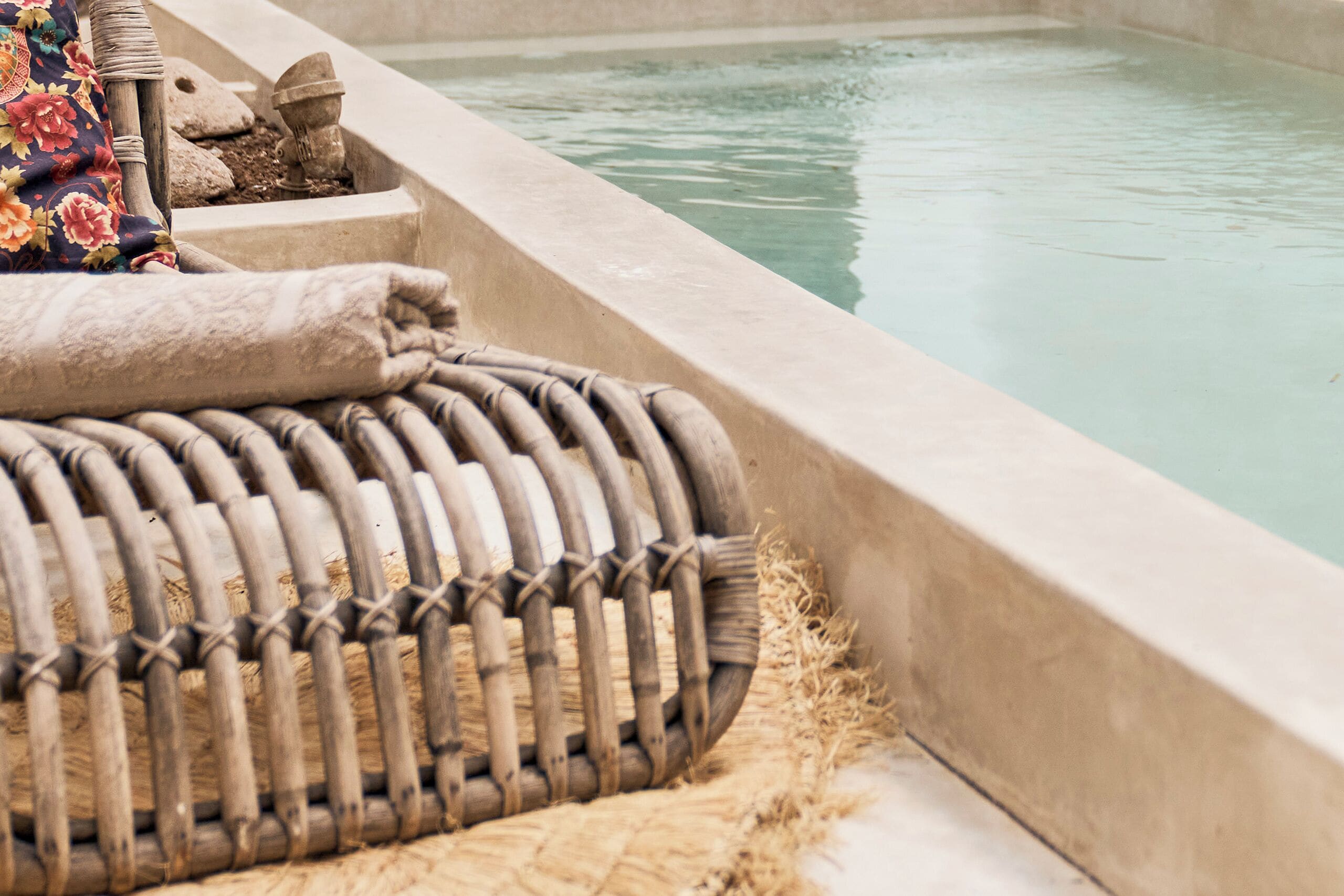 A pool area with a woven bench and a stone structure.