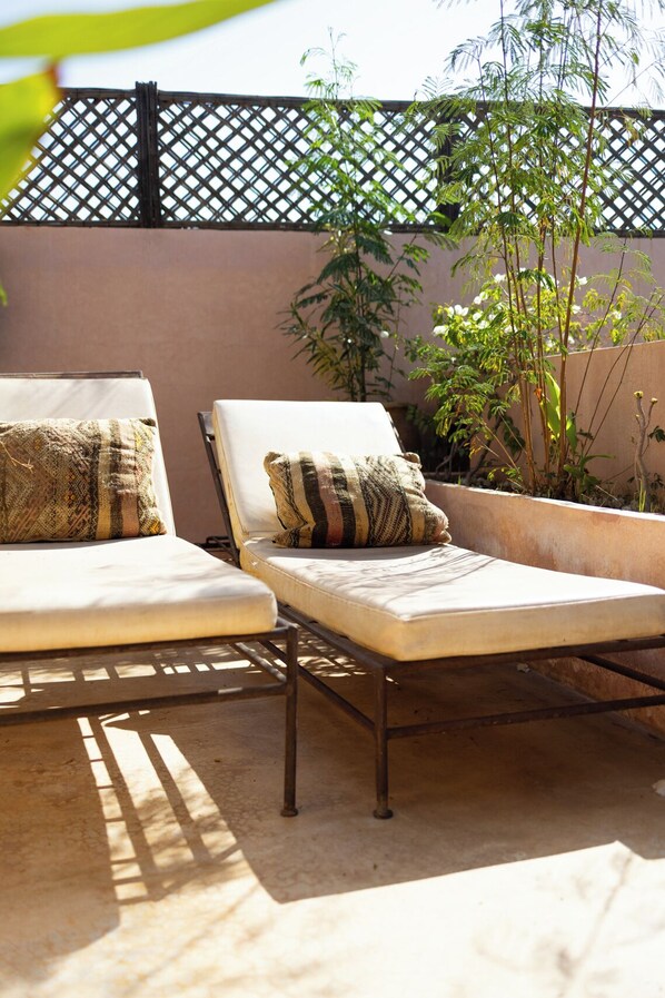 Two lounge chairs with patterned cushions, a metal frame, and a concrete floor.