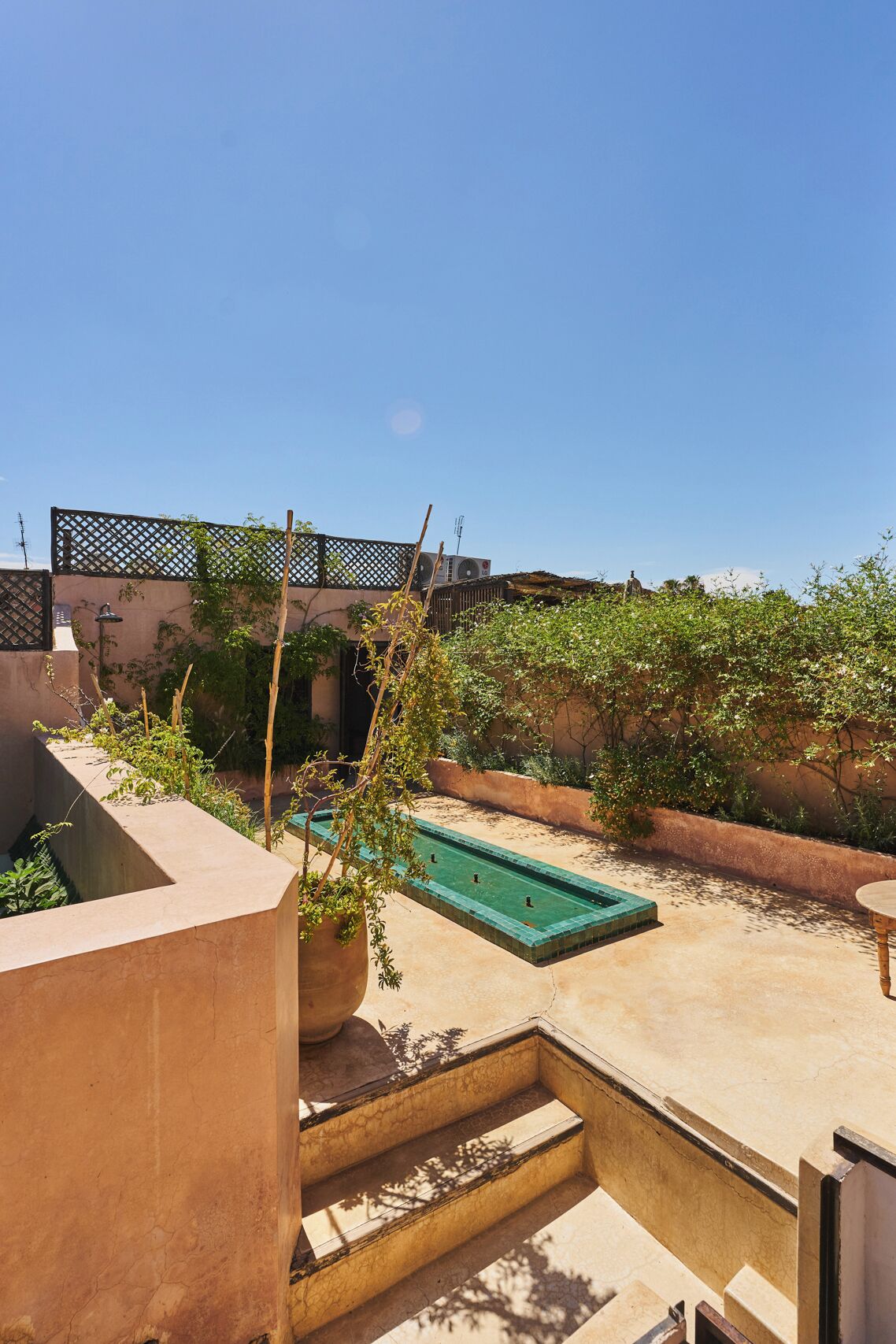 Eine Dachterrasse mit Swimmingpool, Topfpflanzen und Blick auf die Skyline der Stadt.