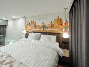 Habitación de hotel moderna con una cama grande, dos lámparas de noche, un mural en la pared y vistas a la ciudad.