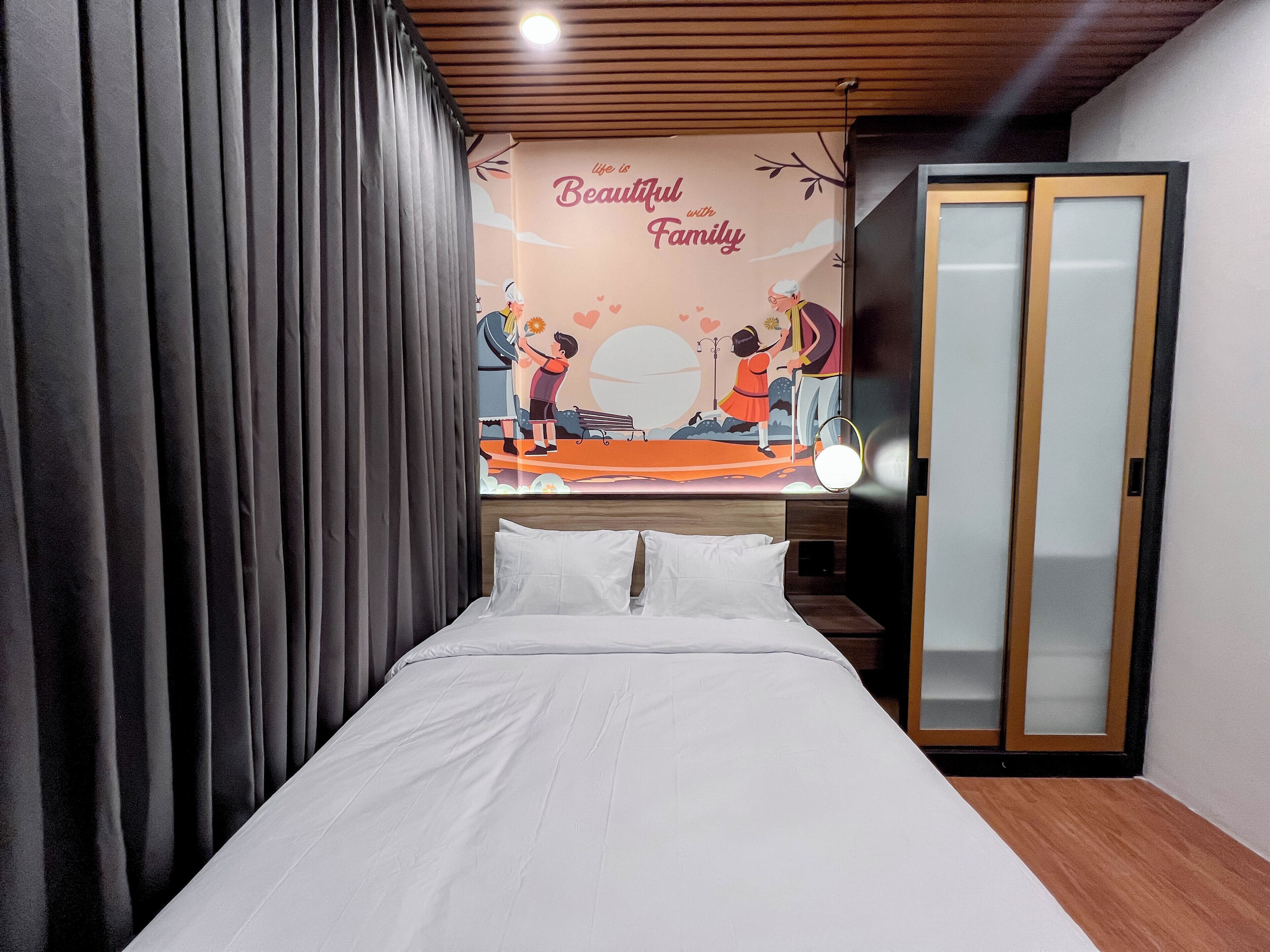 Une chambre d’hôtel avec un lit, une tête de lit en bois, une fresque murale et une porte coulissante.