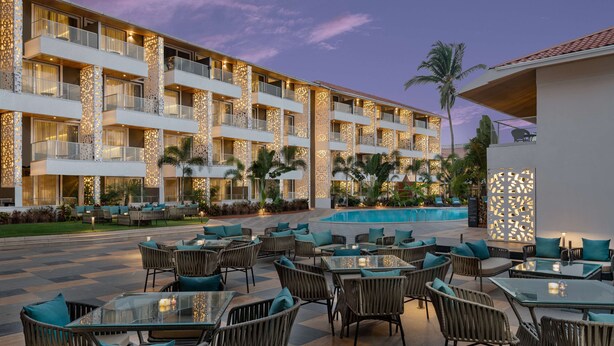 Un hotel con terraza exterior, piscina y fachada bien iluminada.