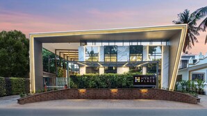 Una entrada de hotel moderna con fachada de vidrio, un camino de ladrillo y un letrero que indica que es un Hyatt Place.