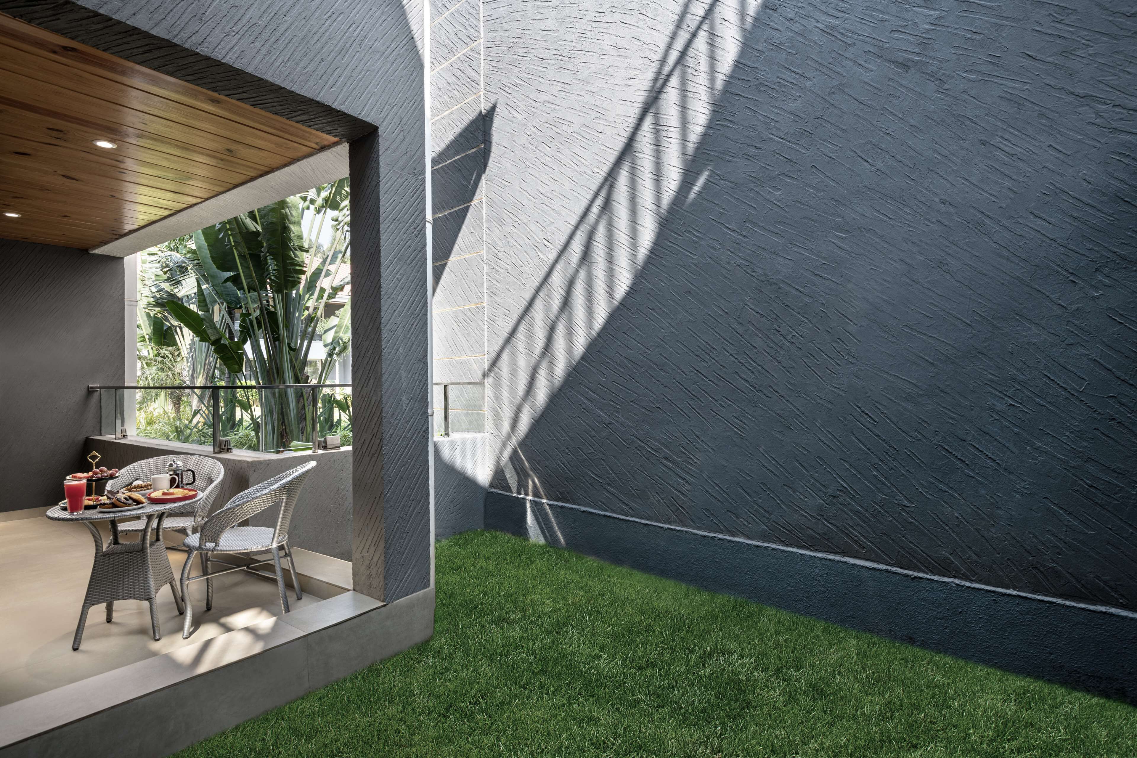 Un espace extérieur moderne aménagé avec une table et des chaises, une surface herbeuse et un mur à texture.