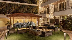 Un patio interior con zona de bar, disposición de asientos y césped artificial verde.