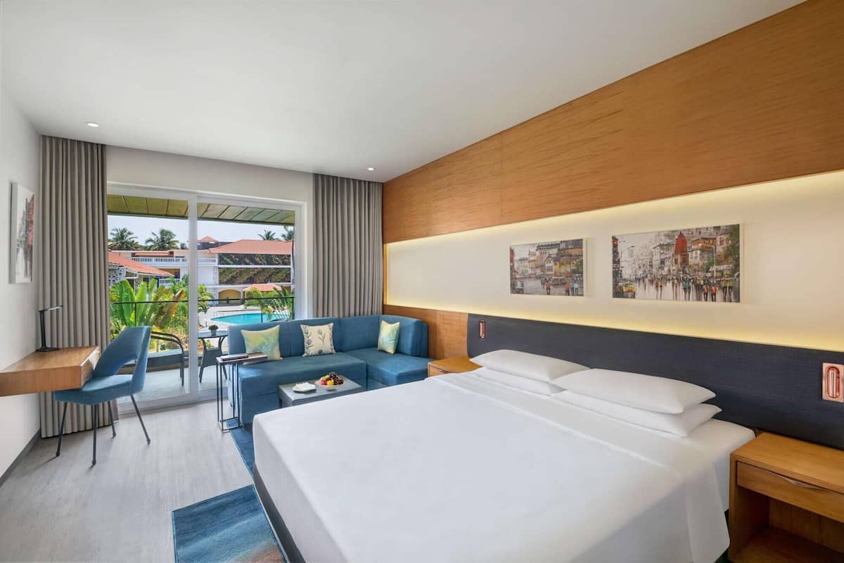Habitación de hotel con cama, sofá, escritorio y vistas al exterior.