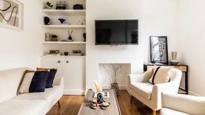 Un salon moderne comprenant un canapé, deux fauteuils, une table basse, un téléviseur à écran plat et une cheminée.