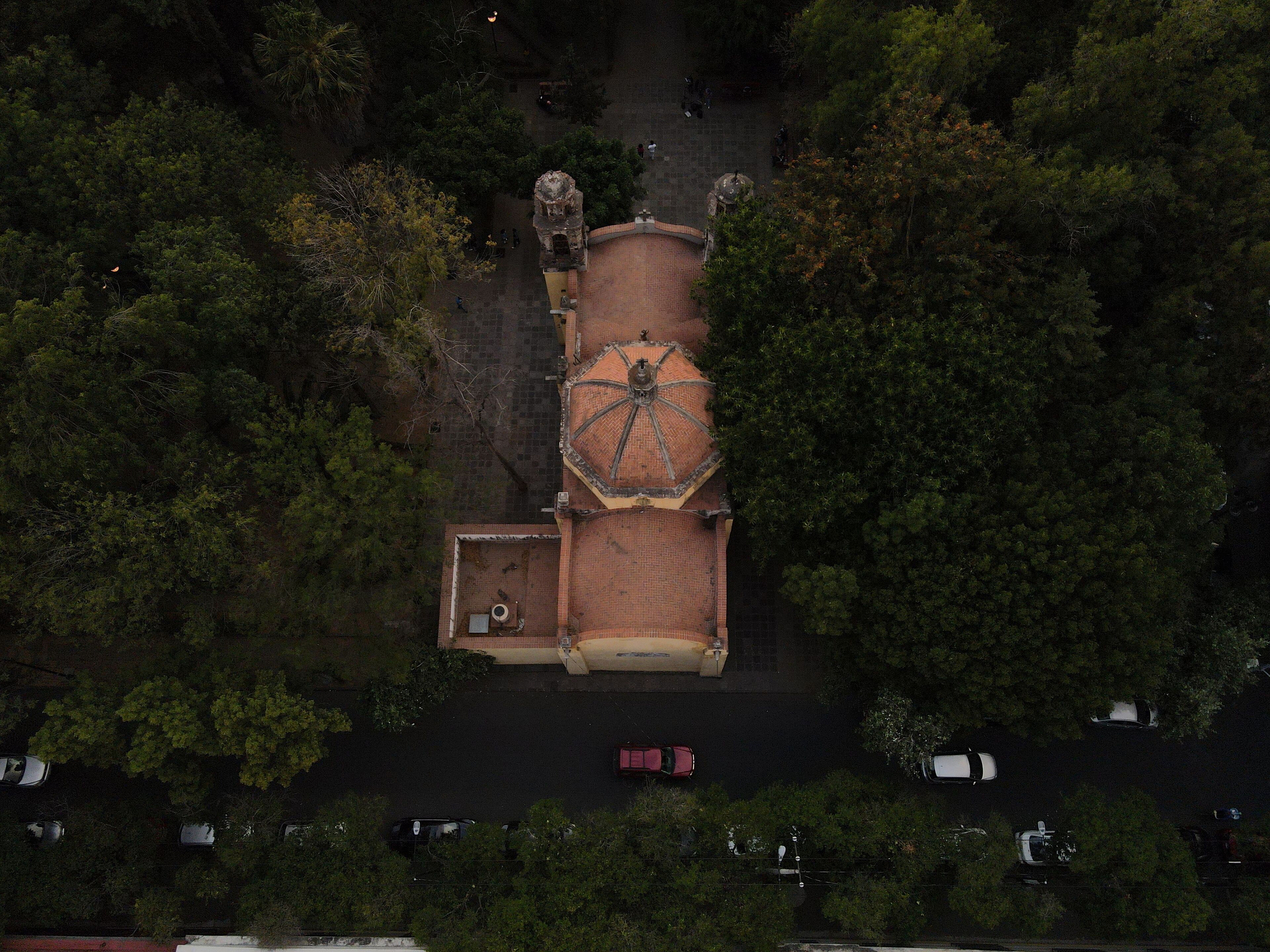 An aerial view of a building with a central tower, surrounded by dense trees.