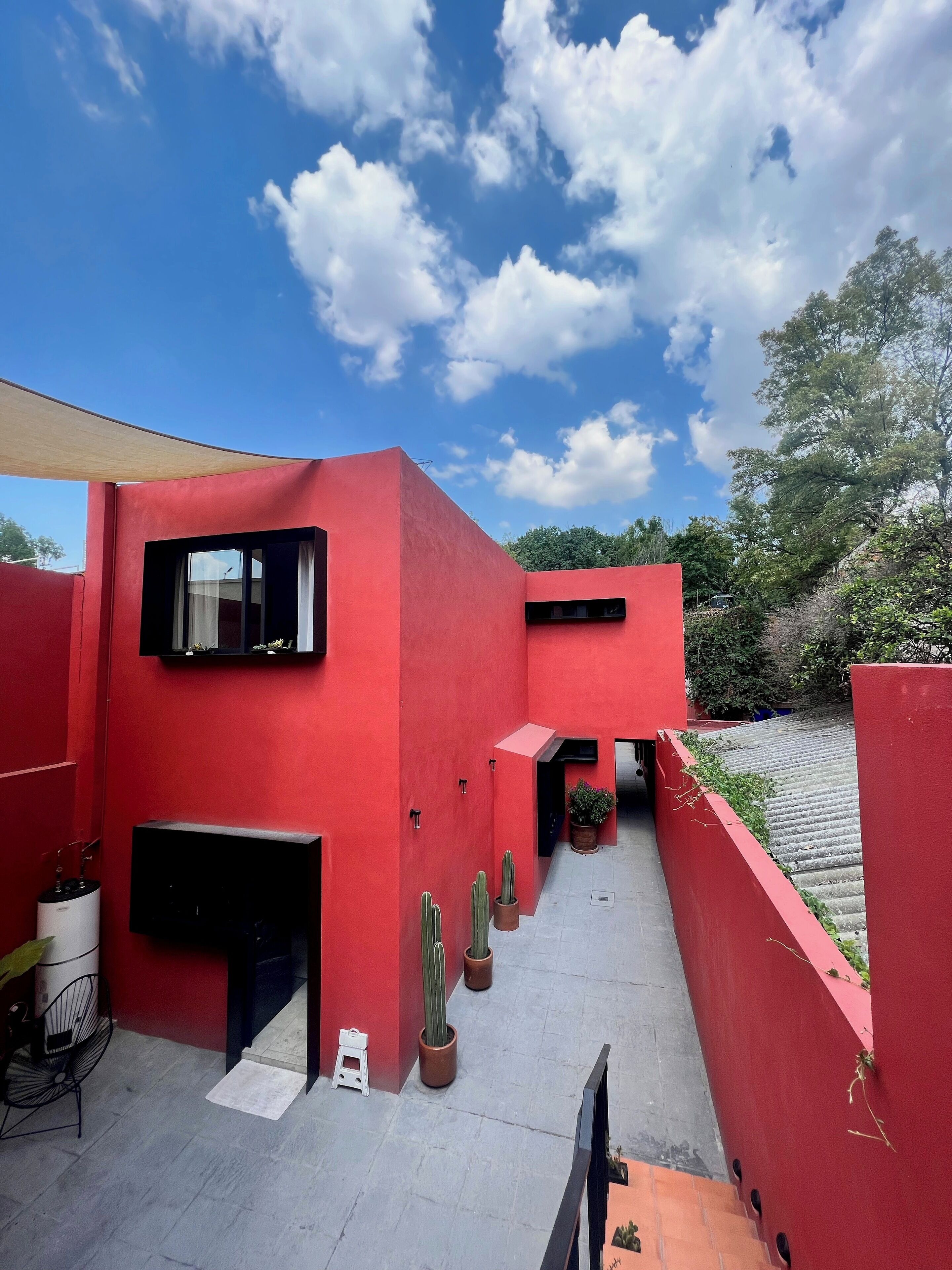 A red building with a flat roof, a small outdoor seating area, and potted plants.
