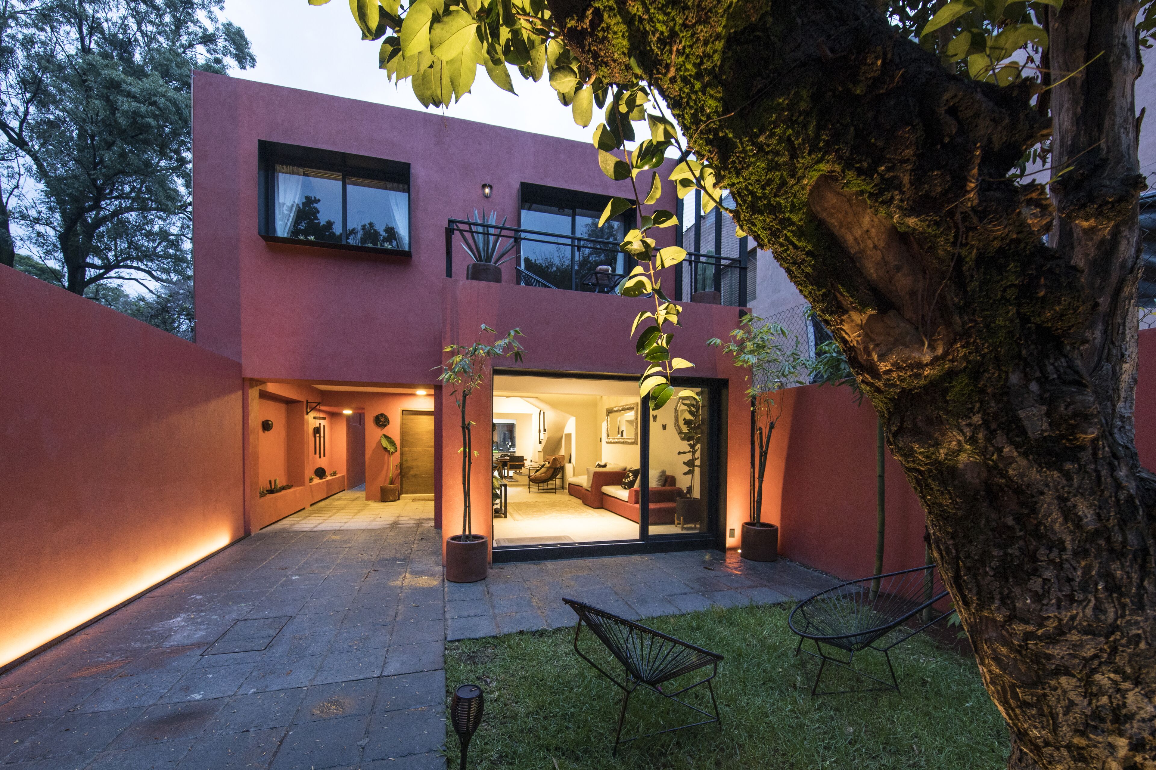 A modern two-story building with a red facade, large windows, and a well-lit interior.